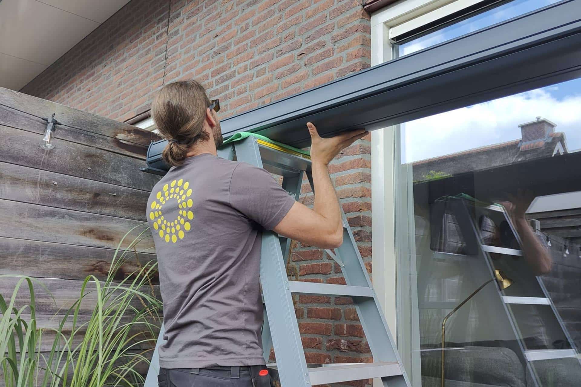 Op de foto is Ruud de Boer bezig met de montage van een knikarmscherm
