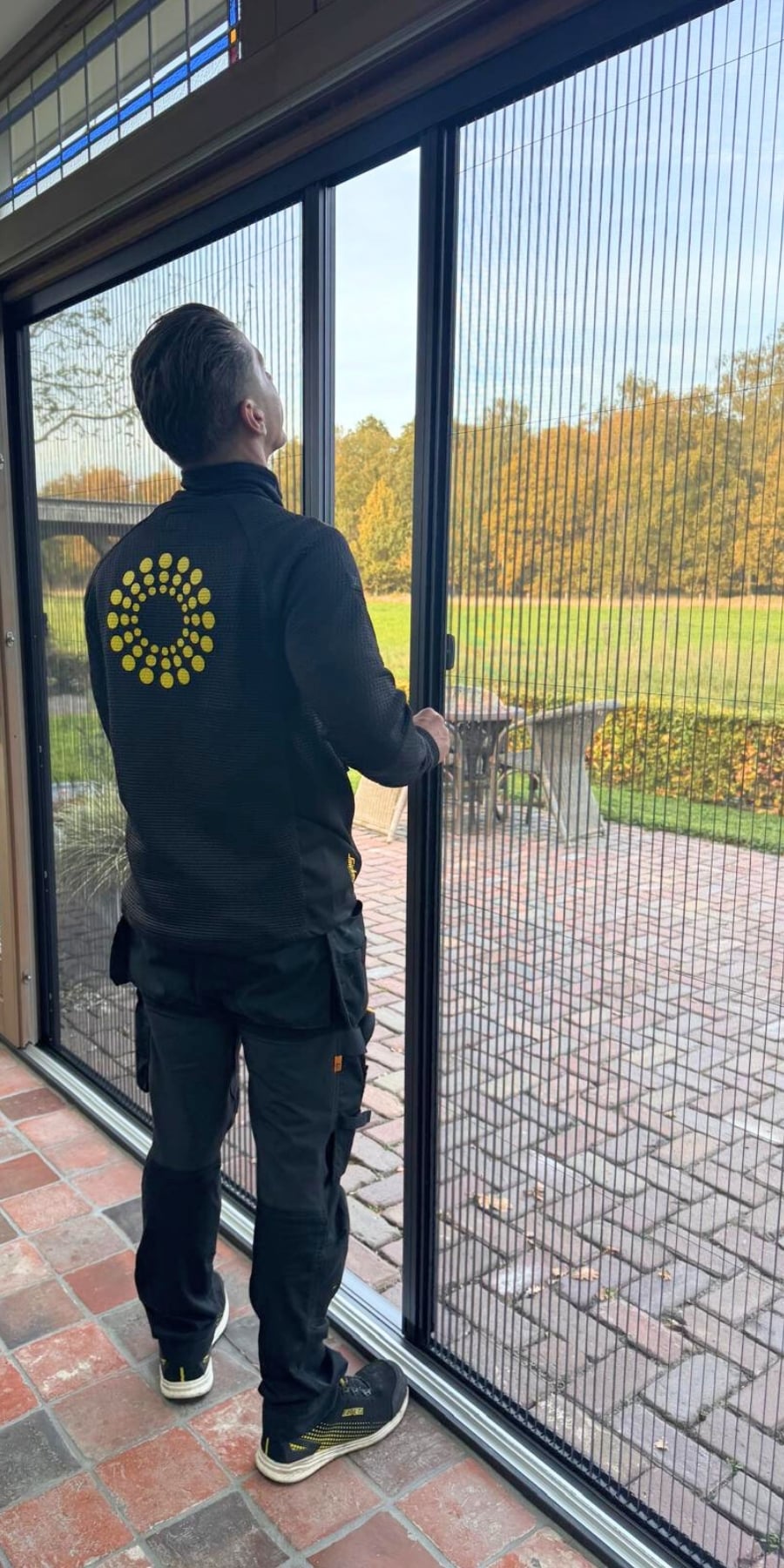 Op deze foto is paul van zonwering de boer te zien die net een plisse hordeur heeft gemonteerd